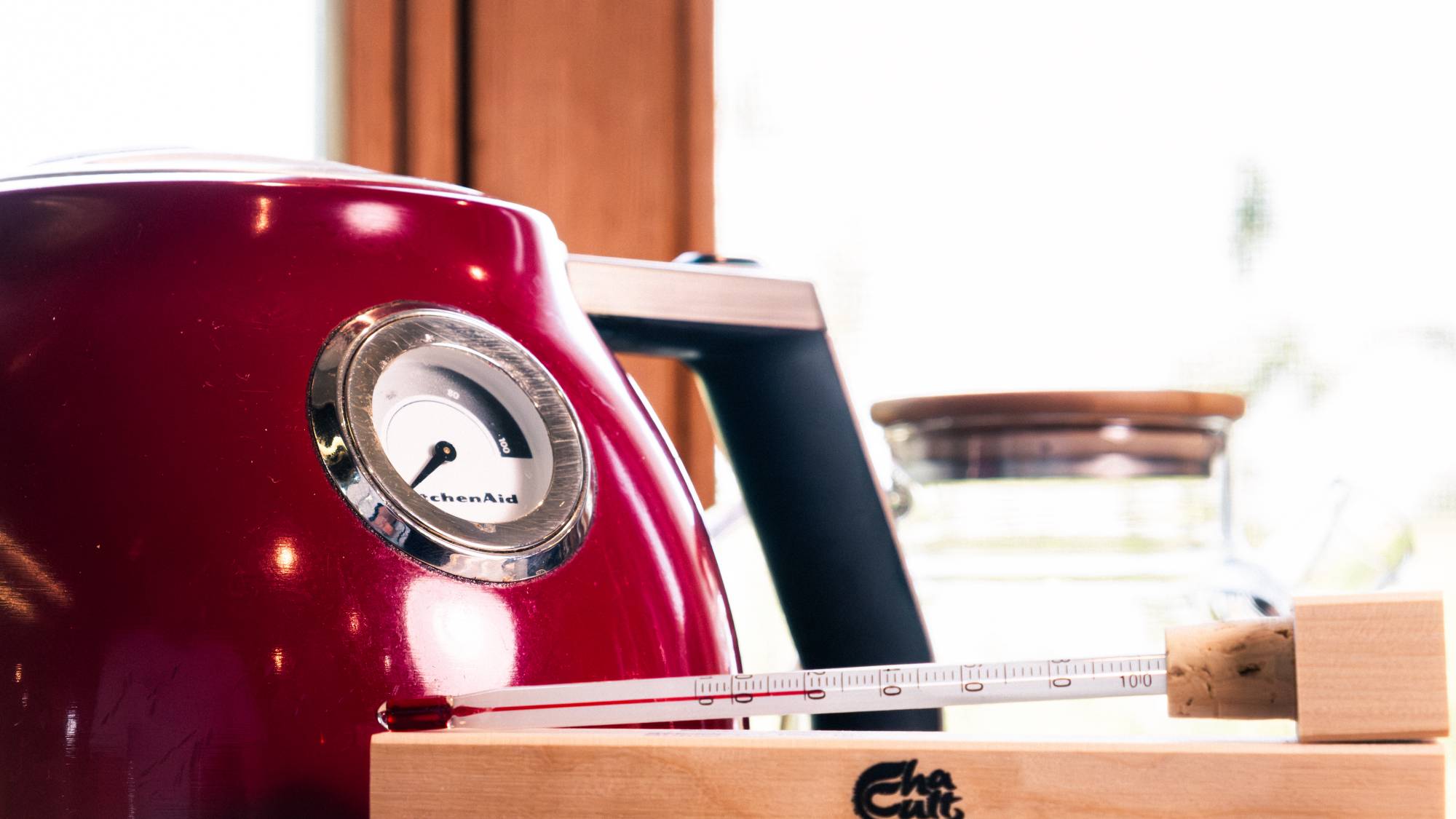 Une bouilloire rouge dans le fond avec un thermomètre pour le thé.